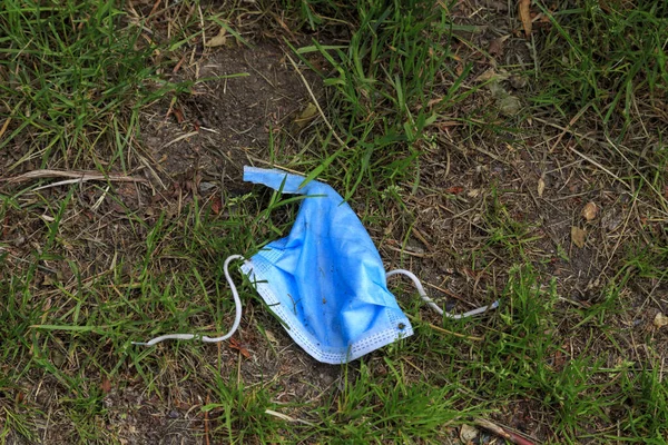 Çimlerin üzerinde cerrahi yüz maskesi..