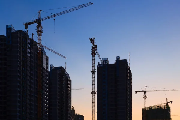 Planta de construcción con muchas grúas al atardecer —  Fotos de Stock