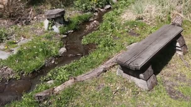 Скамейка для отдыха в лесу на берегу горного ручья . — стоковое видео