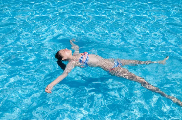 Güzel kız güneşli bir günde yüzme havuzunda dinleniyor.