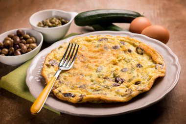 omelette with zucchinis black olives and capers clipart