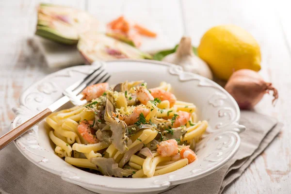 Pasta with shrimp artichoke and lemon grated peel — Stock Photo, Image