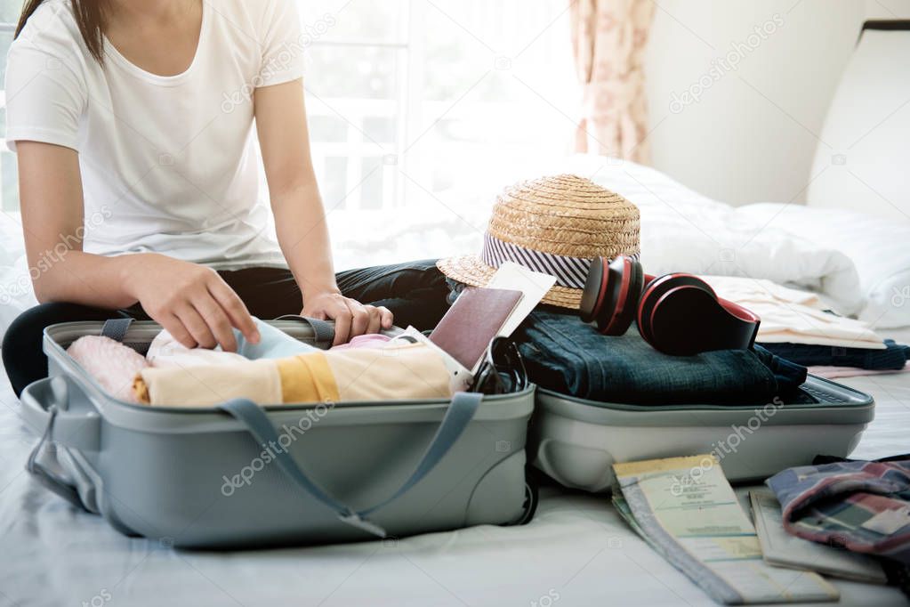 Preparation for vacation or travel. Packing his clothes and stuff into large opened suitcase that almost already full.