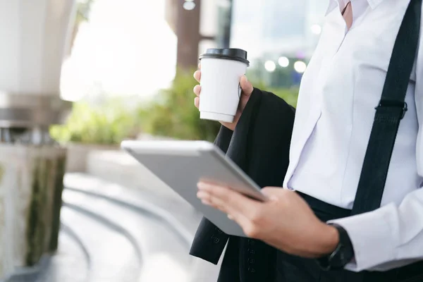 Business working woman in motion.  Business woman walking and holding coffee cup outside office.