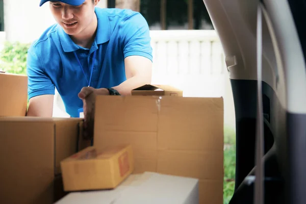 Delivery driver loading his van with boxes outside the warehouse.