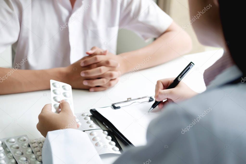Doctor hand holding bottle with pills and writing prescription. Healthcare, medical and pharmacy concept.