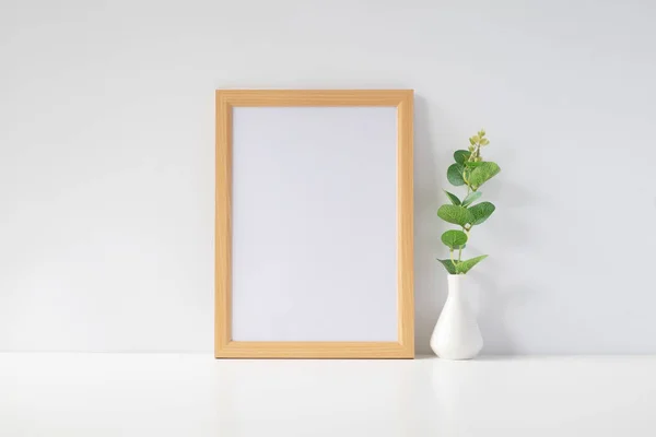 Mock up portrait photo frame with green plant on table, home decoration.