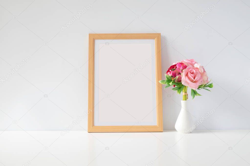 Mock up protrait photo frame with flowers on table, home decoration.