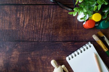 Tasarlamak tasarımcı ve sanatçı sketchbook, suluboya, fırça, kalem ve boyalar ahşap masa üzerinde çalışma alanı. Metin, tasarım için yer. 