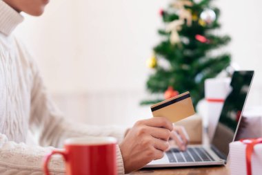Kredi kartı tutan ve online alışveriş yaparken bir adam. Yeni yıl, yılbaşı hediye alışveriş