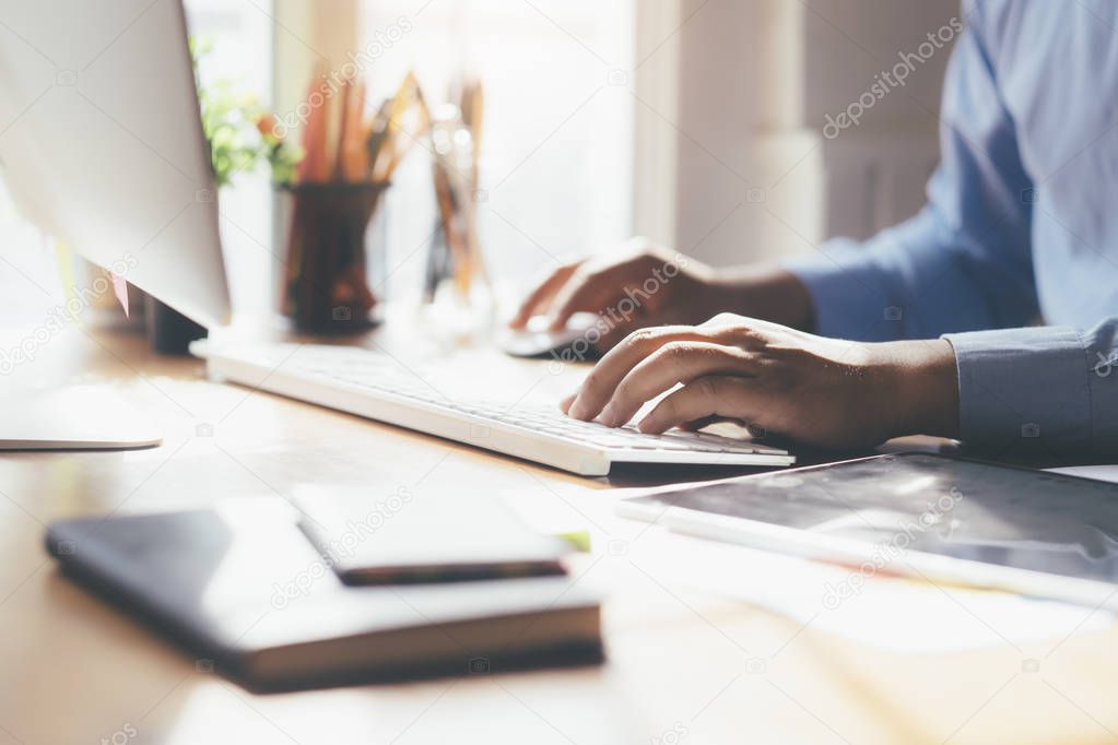 Closeup male hands typing text on a wireless keyboard. Businessman working at the office.