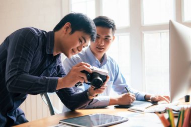 Fotoğraf sanatçısı ve grafik desginer çalışıyoruz. Kameradan yaratıcı seçin resimler. Yaratıcı ofiste fotoğrafları tartışan genç iş arkadaşları