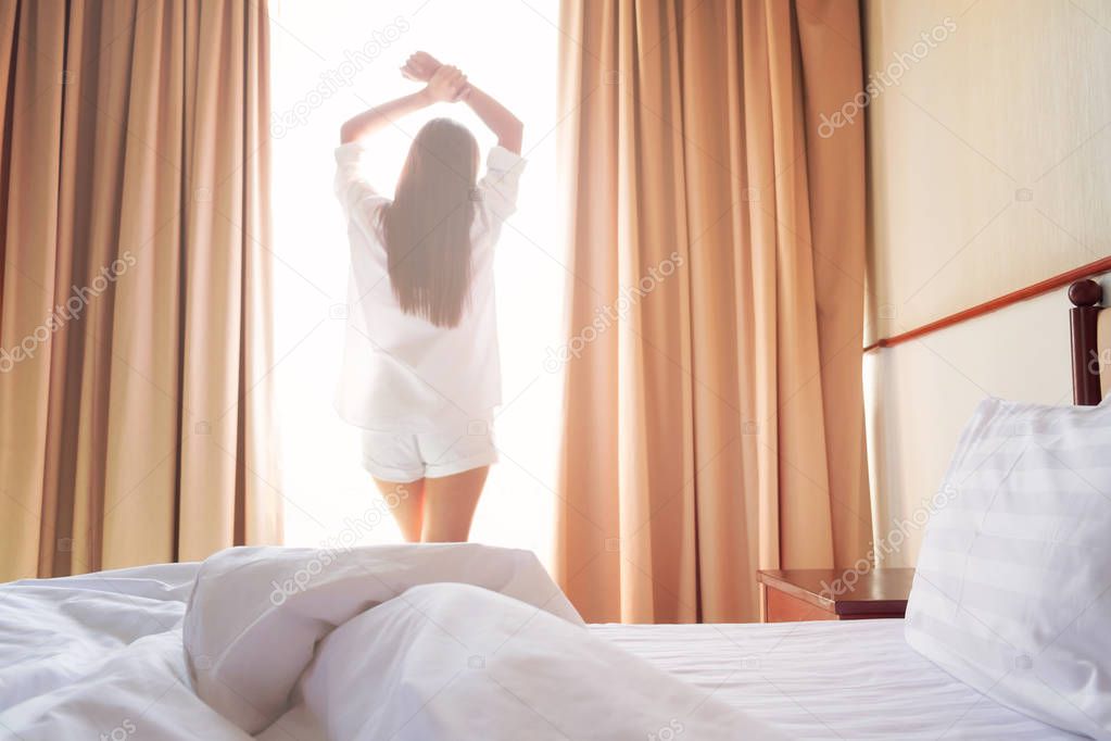 Woman stretching in bed after wake up. Soft light and soft focus to feeling relax and comfortable. 
