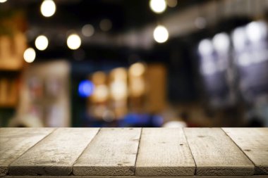 Kahve dükkanındaki mevcut ürün için boş ahşap masa ya da Bokeh imajı olan yumuşak içecek bar bulanık arkaplan