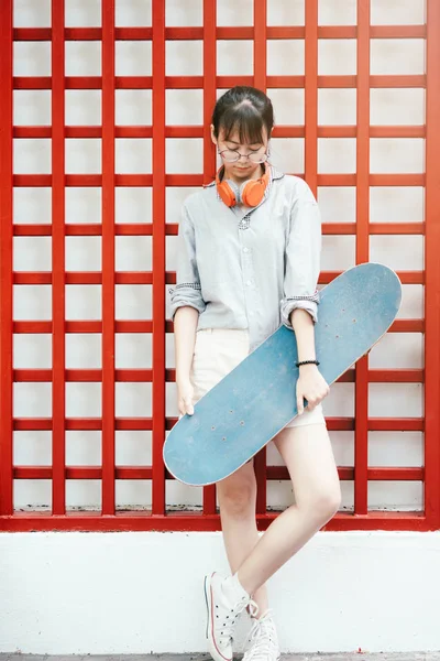 Joven hipster asiático chica sosteniendo monopatín . — Foto de Stock