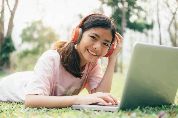 Meisje met draadloze hoofdtelefoon luistert naar de muziek in het park. — Stockfoto