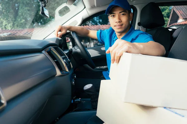 Delivery driver driving car with packages on seat outside the wa — Stock Photo, Image