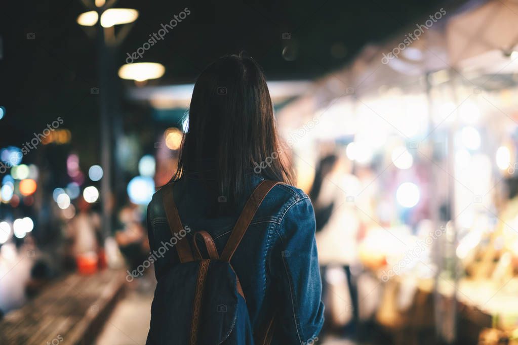 Young traveller woman walking on city street at night.
