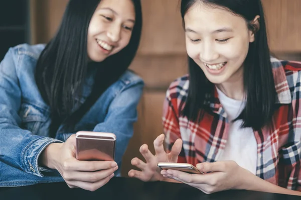 Twee jonge vrouwen met behulp van mobiele telefoons. — Stockfoto