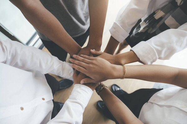 Young people putting their hands together showing unity and team