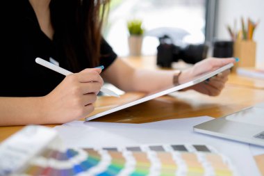 Grafik tasarımcı yaratıcı stüdyo ofisinde masasında çalışıyor. 