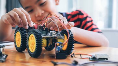 Laboratuvarda robot yaratan konsantre çocuk.