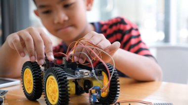 Laboratuvarda robot yaratan konsantre çocuk.
