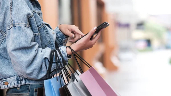 Kadın eli alışverişte cep telefonu kullanıyor..