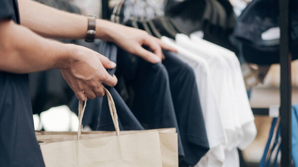 Молодой человек ходит по магазинам и выбирает одежду
