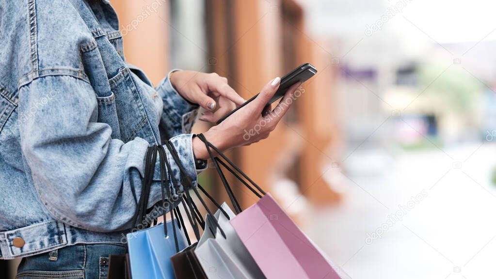 Closeup woman hand using mobilephone in shopping.