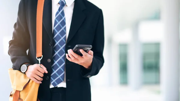 Joven hombre de negocios en el teléfono inteligente caminando en la calle utilizando el texto de la aplicación — Foto de Stock