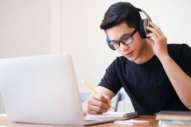 Bilgisayar ve mobil cihaz kullanan genç bir kolaj öğrencisi. Eğitim ve çevrimiçi öğrenim. 