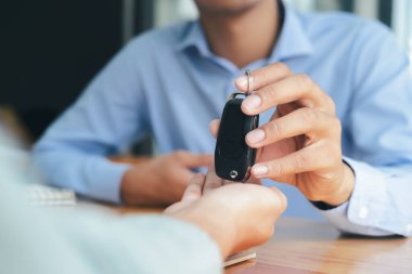 İş konsepti, araba sigortası, araba alıp satma, araba finansmanı, Araç Satış Anlaşması için araba anahtarı. Yeni araba sahipleri erkek satıcılardan anahtar alıyor..