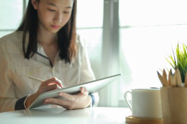 İnternette bilgisayar ve dijital tablet kullanan genç bir kolaj öğrencisi. Eğitim ve çevrimiçi öğrenim.