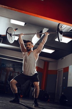 Genç adam havai bodur egzersiz halter ile çapraz eğitim saatinde