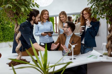 Grup genç mühendis konusunda alternatif enerji projesi Minyatürler yel türbinleri ile masada konuşurken