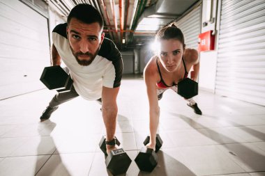 Push-up yapıyor genç kas çift Dambıl ile zor egzersiz spor salonunda egzersiz