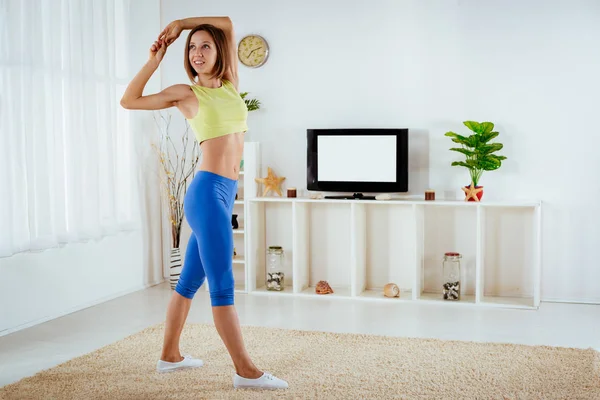 Önünde Oturma Odasında Genç Fitness Kadının Yapması Germe Egzersizleri — Stok fotoğraf