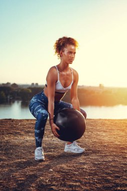 Genç fitness kadının günbatımında duvar topu ırmak ile egzersiz yapması
