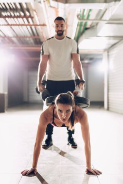 Kaslı kadın ile kişisel antrenör garaj spor salonunda egzersiz yapıyor