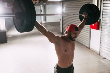 Genç kaslı adam yüksek çekme egzersiz halter ile çapraz eğitim saatinde