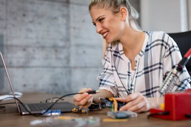 Genç kadın teknisyeni havya tarafından elektronik donatımın tamiri üzerinde duruldu