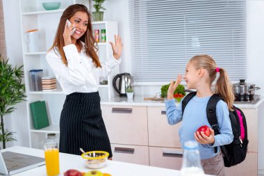 küçük kız çok çalışan anne telefon ederek ve bilgilerini dizüstü bilgisayarda kontrol ederken kahvaltı