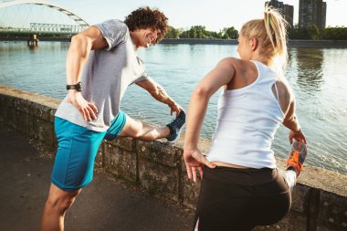 Genç mutlu çift germe yapıyor nehir kenarında güneş doğarken egzersiz.