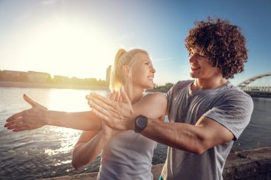 Genç mutlu çift germe yapıyor nehir kenarında güneş doğarken egzersiz.