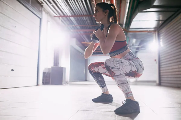 Young muscular woman doing exercise with kettlebell on hard training