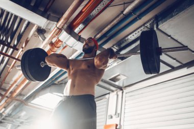 Genç kaslı adam yüksek çekme egzersiz halter ile çapraz eğitim saatinde
