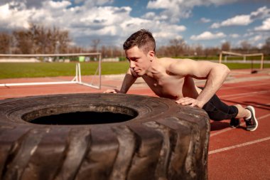 Genç kaslı adam eğitim kasları Stadı için büyük lastik kaldırma