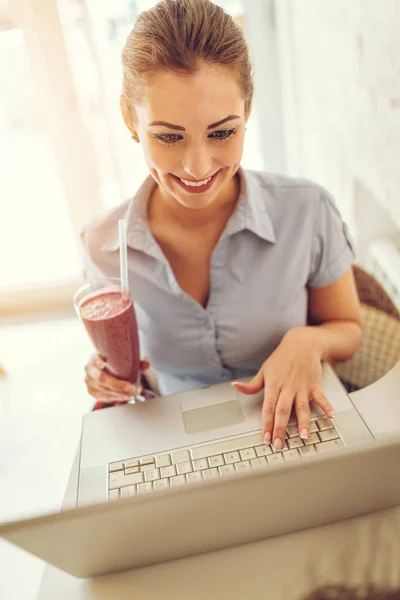 Jonge Glimlachende Zakenvrouw Werken Bij Laptop Drinken Fruit Smoothie — Stockfoto