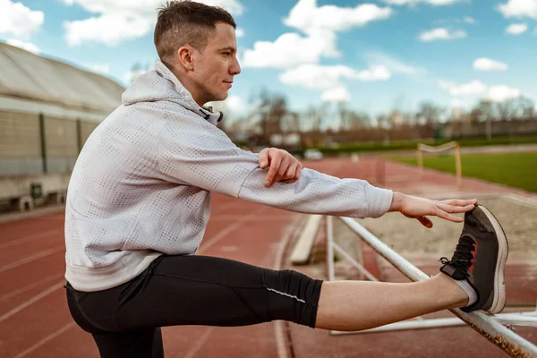 Aktif genç germe bacaklar üzerinde boş Stadyumu koşu daha önce adam